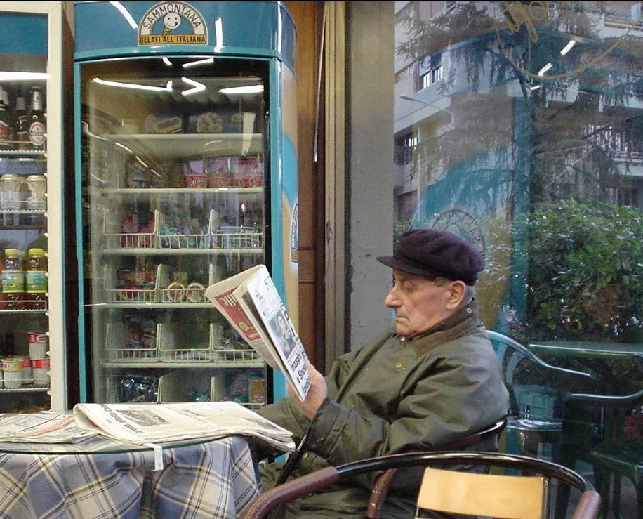Man reading a local newspaper at a street cafe